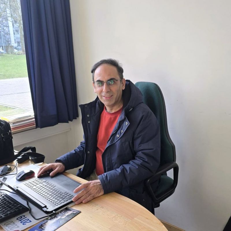 Abolfazl sitzt an einem Schreibtisch.