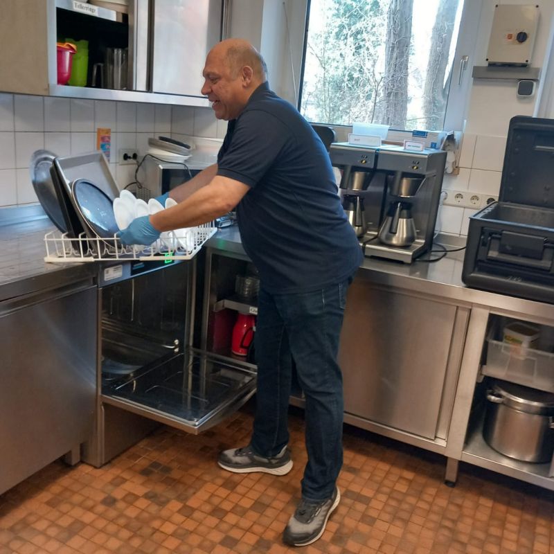 Hossein hebt den Geschirrkorb aus der Spülmaschine.